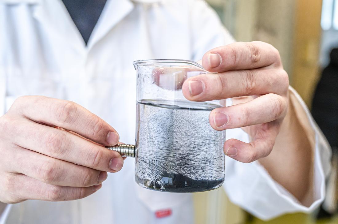Ferrofluid pulled into spikes by a magnet held against a beaker